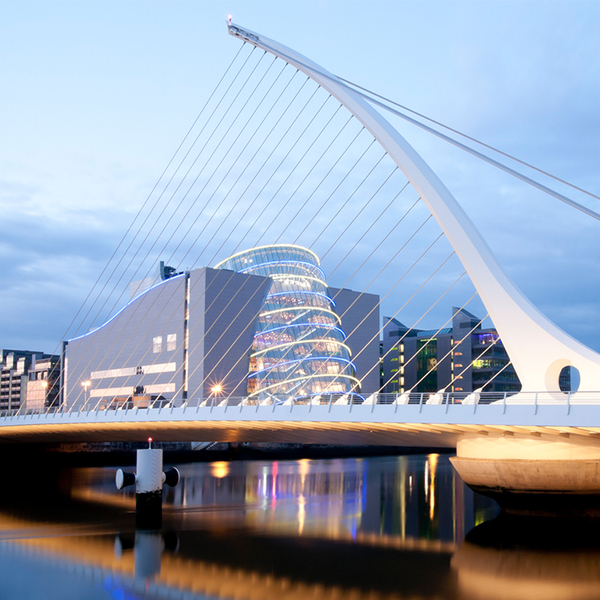 Samuel Beckett Bridge in Dublin after sunset. Modern bridge with modern buildings and skyscrapers in the backround.