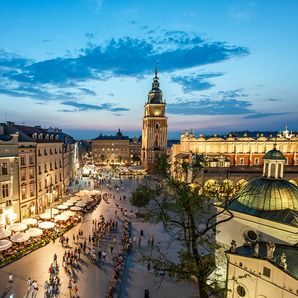 A view of the market square in Krakow at sunset with people walking around 
