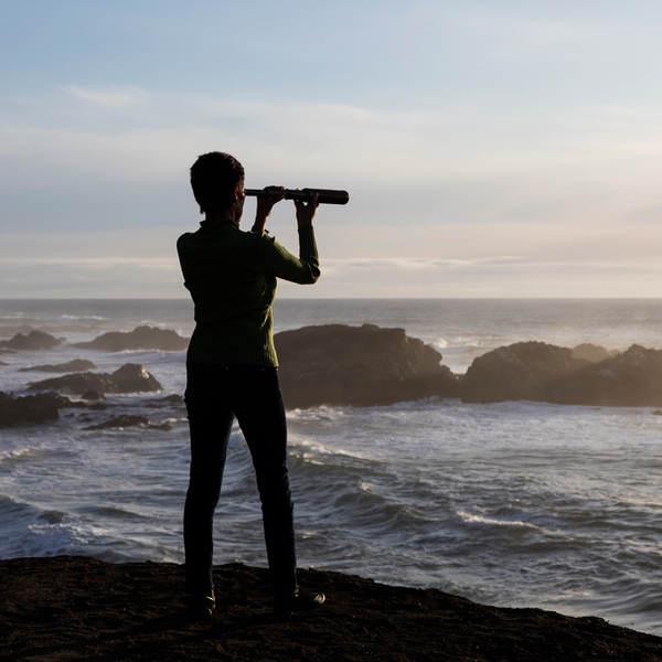 A woman with binocular by the sea shore