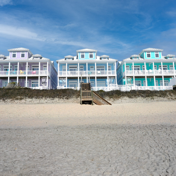 Colorful beach houses on a sandy beach under a blue sky on the North Carolina coast