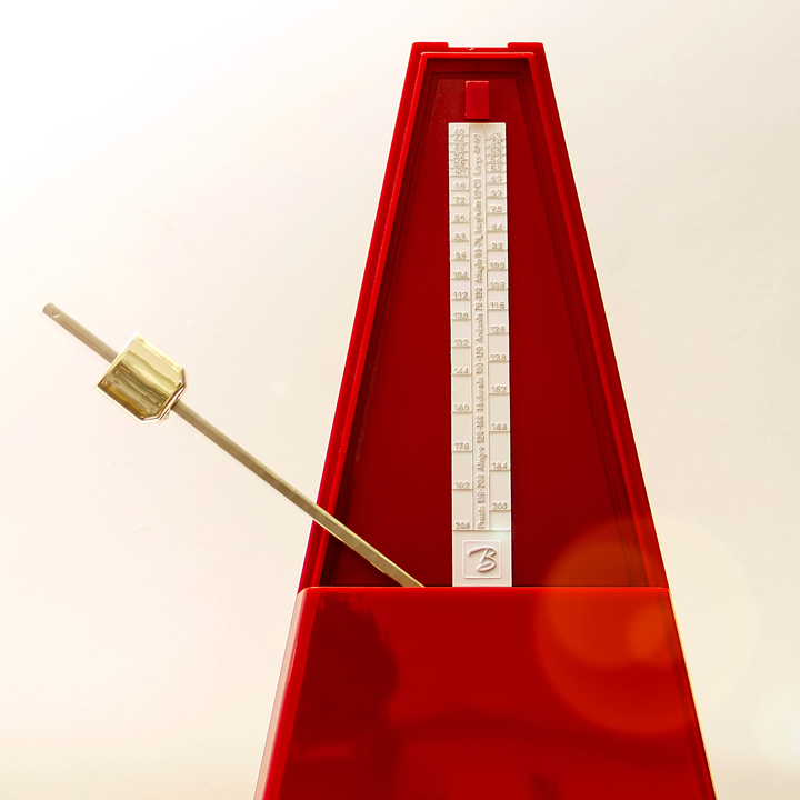Mechanical metronome of red color on a light background 