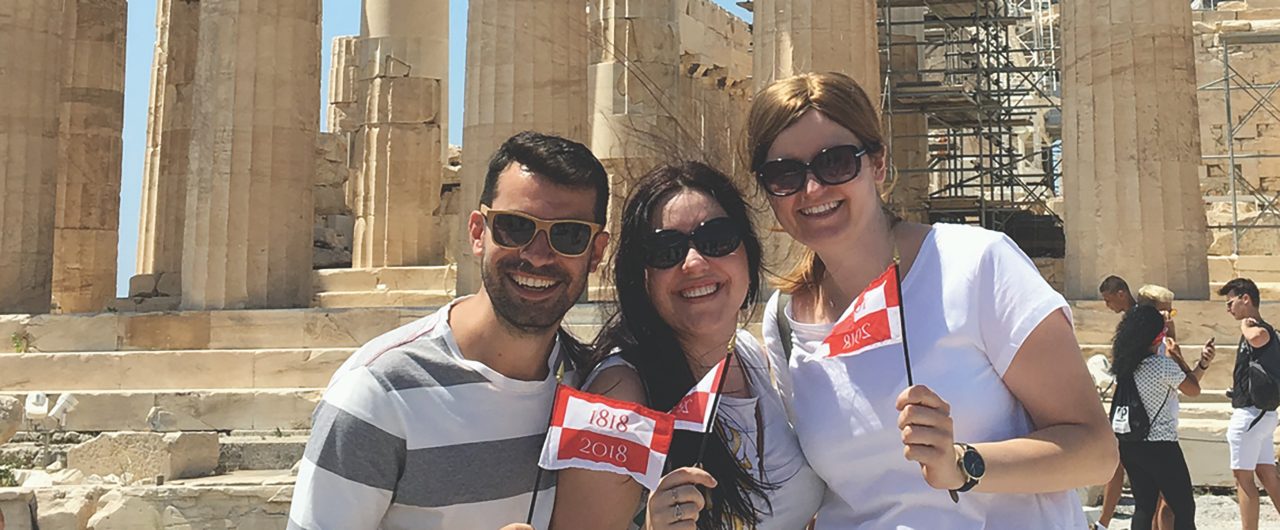 BBH employees at Acropolis holding BBH flags-Banner