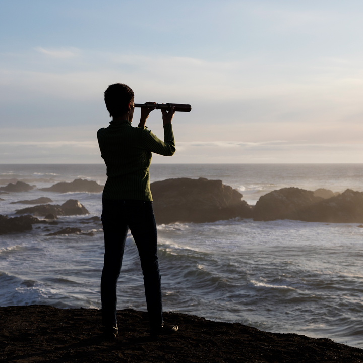 A woman with binocular by the sea shore