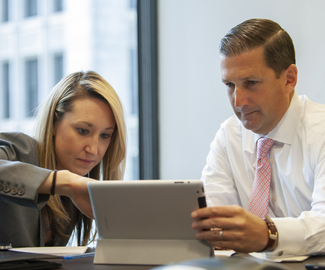 Two BBH employees working on a tablet.